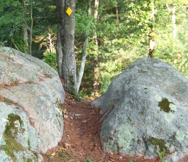 The Mack Trail leads between two boulders on its descent from the rocky outcropping observation area.